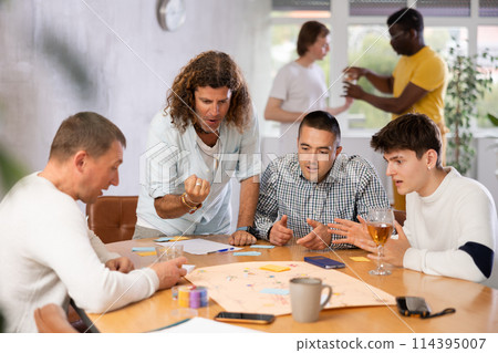 Cheerful man playing board game with male friends 114395007