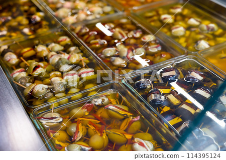 Pickled stuffed olives in glass containers on market counter Pickled stuffed olives in glass containers on market counter 114395124