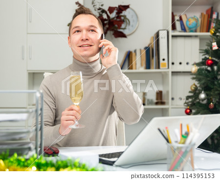 Cheerful office worker talking on phone, celebrating Christmas in office 114395153
