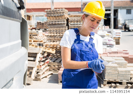 Woman checking order list near car at construction store 114395154