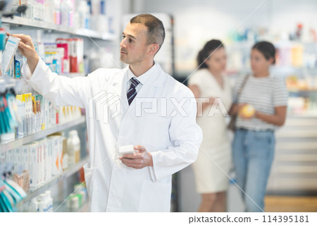 Young male pharmacist choosing convenient medicament in box 114395181