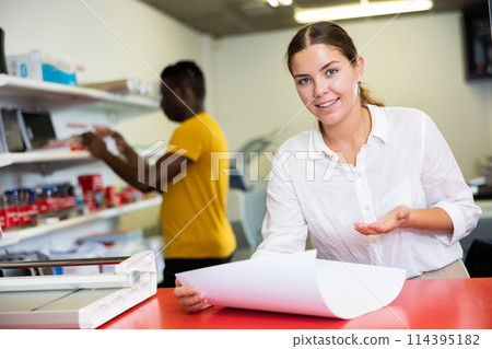 Focused young woman in white shirt checking the print quality and accepting color proofs in typography 114395182