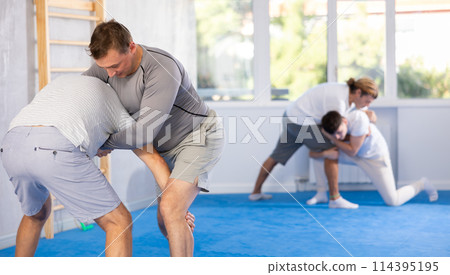 Man and senior man athletes in pair conduct training battle in oriental fighting technique Man and senior man athletes in pair conduct training battle in oriental fighting technique 114395195