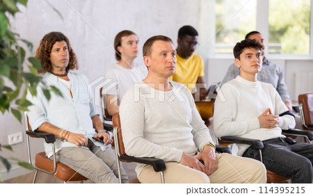 Group of men attentively listens to a lecture in the audience Group of men attentively listens to a lecture in the audience 114395215