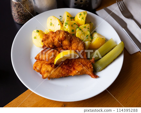 Chicken fillet in batter with Parmesan with potatoes and pickled cucumbers Chicken fillet in batter with Parmesan with potatoes and pickled cucumbers 114395288