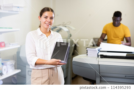 Smiling young female typographer showing new notepads in the middle of the typography 114395293