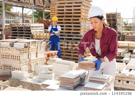 Concentrated asian woman manager laying tiles in a warehouse 114395296