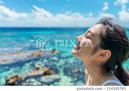 一位旅行的年輕女子在美麗的夏日大海和陽光下感到舒適。 114395763