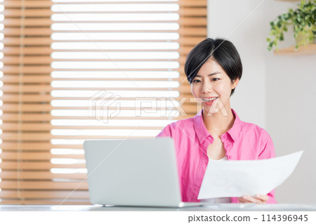 A woman teleworking in the living room. 114396945