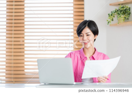 A woman teleworking in the living room. 114396946