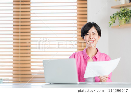 A woman teleworking in the living room. 114396947