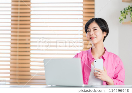 A woman teleworking in the living room. 114396948