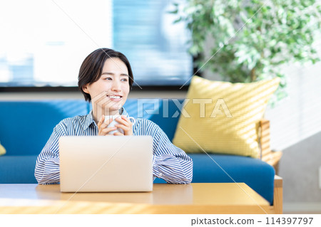 A woman operating a laptop in the living room. A woman operating a laptop in the living room. 114397797