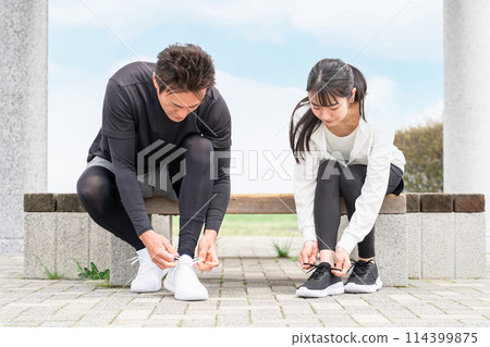 Asian man and woman tying shoelaces and preparing for exercise 114399875