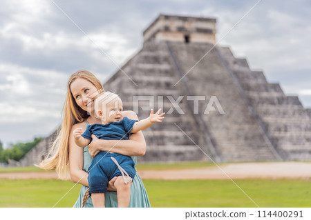 Beautiful tourist woman and her son baby observing the old pyramid and temple of the castle of the Mayan architecture known as Chichen Itza these are the ruins of this ancient pre-columbian 114400291