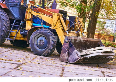 Excavator bulldozer loads old concrete slabs on road repair Excavator bulldozer loads old concrete slabs on road repair 114401259