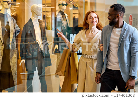 smiling beautiful wwoman asking her boyfriend to buy something for her the shop 114401308