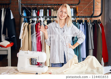 cheerful blonde woman holding scissors in hands cheerful blonde woman holding scissors in hands 114401653