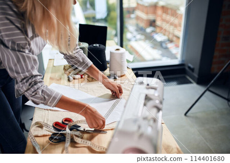 young tailor measuring fabric and scetch 114401680