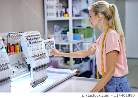 young seamstresses in modern studio workshop, preparing tailoring machine for work 114401990