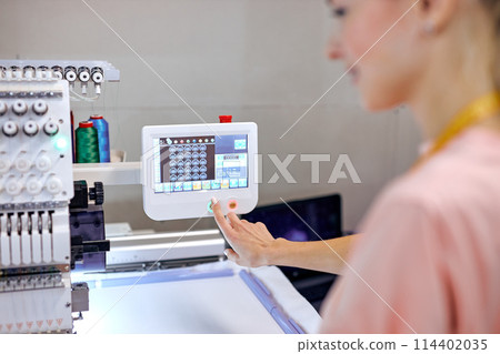seamstresses at workshop, preparing modern machine for work, focus on equipment 114402035