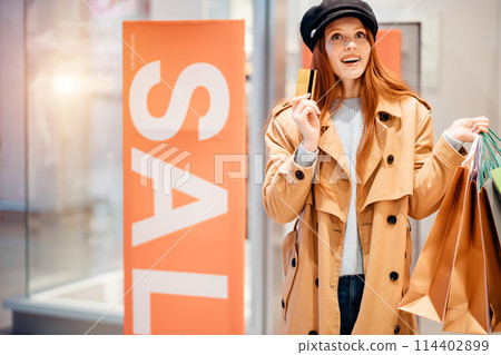 happy young female with shopping bags in shop 114402899