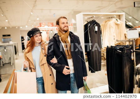 beautiful wife and husband walk together in clothes shop 114402970