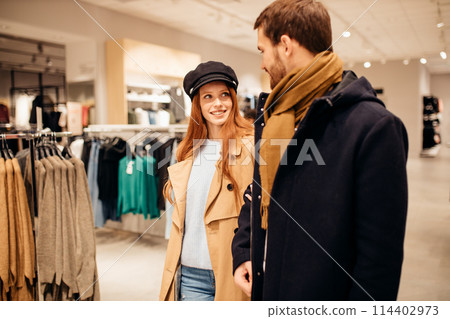 beautiful wife and husband walk together in clothes shop 114402973