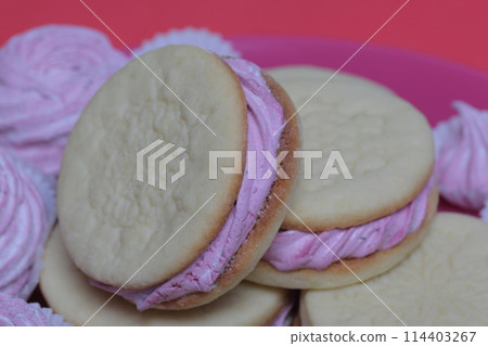 Cooked marshmallow sandwiches. They lie on plate. Next on the plate is a marshmallow of various sizes. 114403267