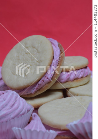 Cooked marshmallow sandwiches. They lie on plate. Next on the plate is a marshmallow of various sizes. 114403272
