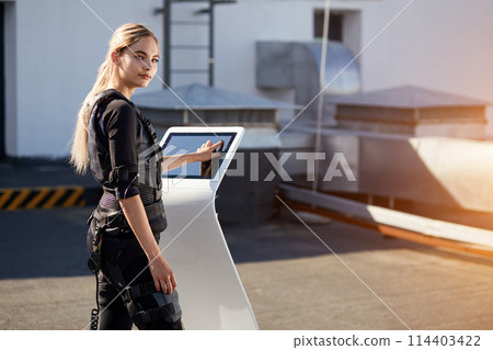 Back view photo of pleasant woman pushing on screen on EMS machine 114403422