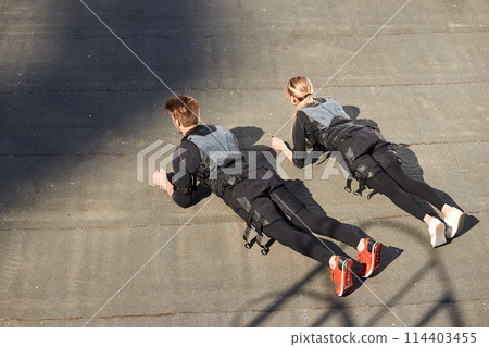 top view photo. two athletes in EMS suits doing push-ups top view photo. two athletes in EMS suits doing push-ups 114403455