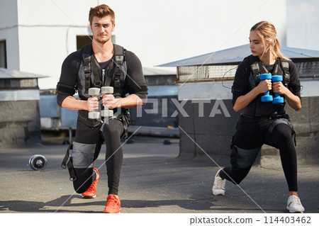 two active athletes are doing lunge exercises with dumbbells two active athletes are doing lunge exercises with dumbbells 114403462