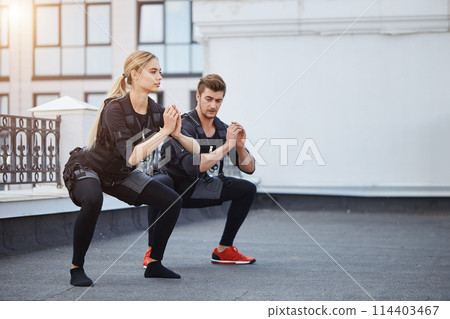 two fit young people bending knees to full squat position 114403467