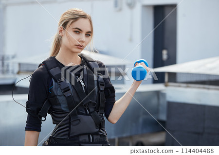 young fair-haired woman performing electric muscular stimulation training young fair-haired woman performing electric muscular stimulation training 114404488