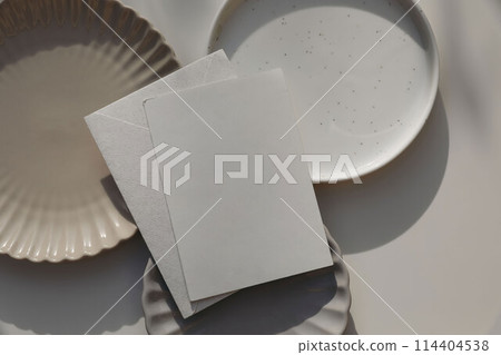 Blank greeting card, invitation mockup, envelope in sunlight. Different plates on beige table background. Soft shadows. Neutral still life, web banner. Food, restaurant, craft concept. Flat lay, top. Blank greeting card, invitation mockup, envelope in sunlight. Different plates on beige table background. Soft shadows. Neutral still life, web banner. Food, restaurant, craft concept. Flat lay, top. 114404538
