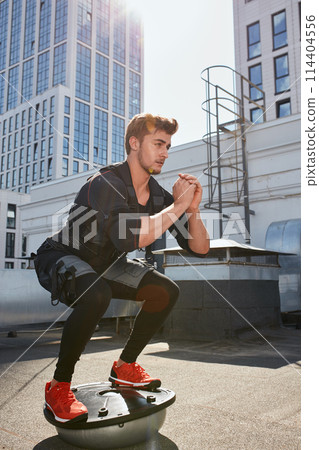 handsome man doing squats on fit ball. muscle stimulation handsome man doing squats on fit ball. muscle stimulation 114404556