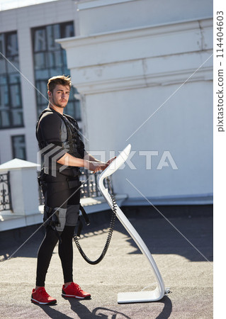 slim handsome man is looking at the camera while standing near the EMS device slim handsome man is looking at the camera while standing near the EMS device 114404603