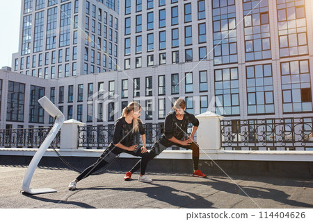 a hardworking couple is doing stretches outdoors a hardworking couple is doing stretches outdoors 114404626