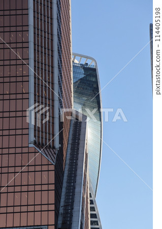 Futuristic design part of skyscrapers against a clear blue sky. Abstract facade design. Futuristic design part of skyscrapers against a clear blue sky. Abstract facade design. 114405198
