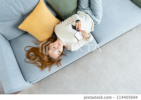 Young Woman Enjoying Online Shopping On Couch Using Smartphone And Credit Card At Home Young Woman Enjoying Online Shopping On Couch Using Smartphone And Credit Card At Home 114405694