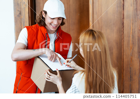 Delivery Courier Handing Over Package To Woman At Home 114405751