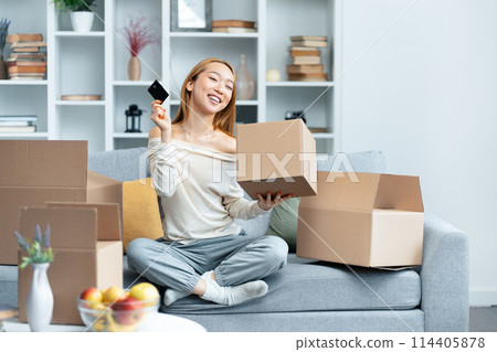 Happy Young Woman Unpacking Boxes in New Apartment 114405878