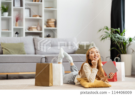 Young Woman Relaxing With Shopping Bags In Modern Living Room 114406009