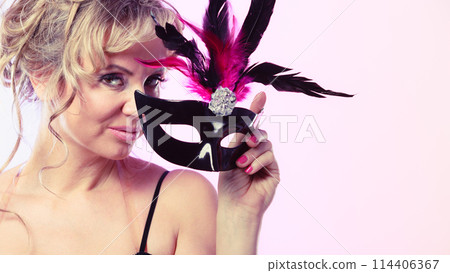 Woman middle aged holds carnival mask. 114406367