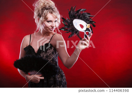 Woman holding carnival mask feather fan in hand Woman holding carnival mask feather fan in hand 114406398