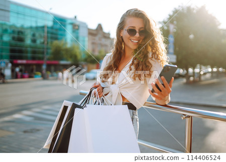 Beautiful woman with shopping bags makes selfie. Woman walking after shopping. Black friday. 114406524