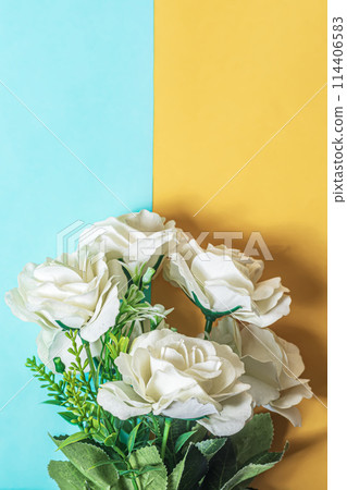 White roses bouquet on blue and yellow background. Flat lay. Vertical shot 114406583