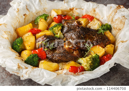 Baked Lamb with potatoes, broccoli, onions and peppers in parchment close-up in a frying pan. Horizontal Baked Lamb with potatoes, broccoli, onions and peppers in parchment close-up in a frying pan. Horizontal 114406708