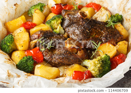 En papillote Lamb with potatoes, broccoli, onions and peppers in parchment close-up in a frying pan. Horizontal 114406709